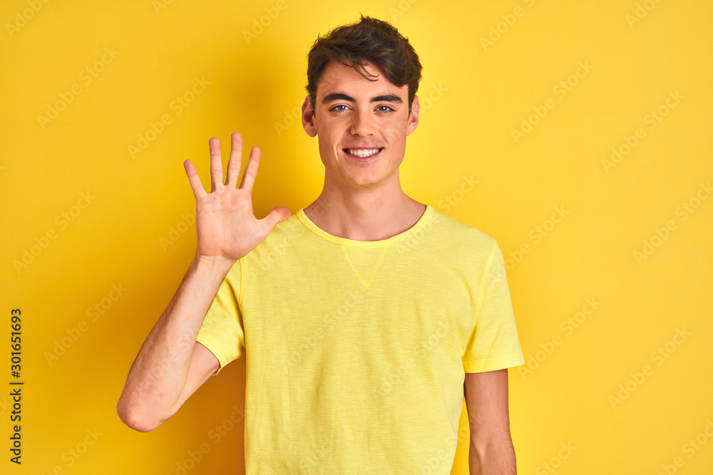 Teenager boy wearing yellow t-shirt over isolated background showing and pointing up with fingers number five while smiling confident and happy. Teenager boy wearing yellow t-shirt over isolated background showing and pointing up with fingers number five while smiling confident and happy.