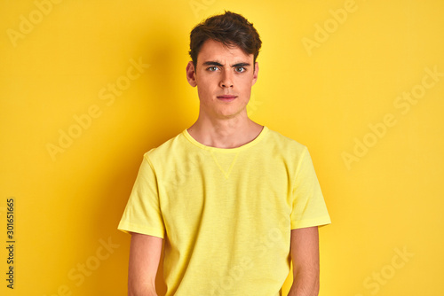Teenager boy wearing yellow t-shirt over isolated background skeptic and nervous, frowning upset because of problem. Negative person.