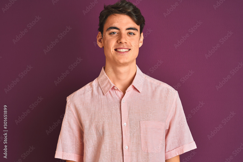 Teenager boy wearing pink shirt standing over purple isolated background with a happy and cool smile on face. Lucky person. Teenager boy wearing pink shirt standing over purple isolated background with a happy and cool smile on face. Lucky person.