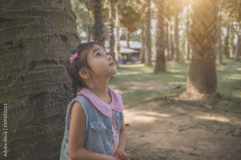 little girl is standing look a palm tree little girl is standing look a palm tree