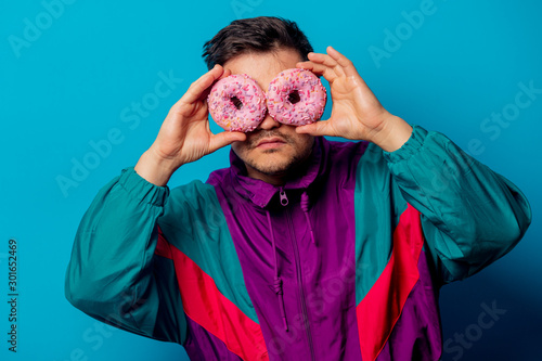 Handsome man in 90s jacket with donnut on blue background photo