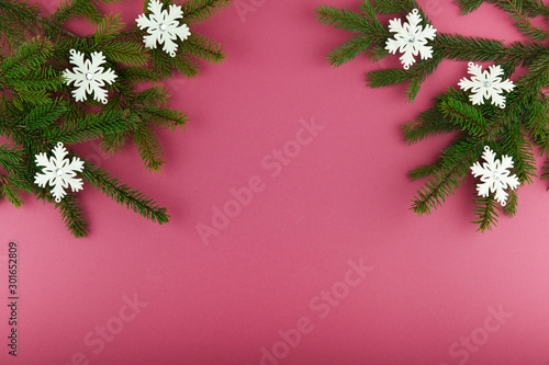 Christmas tree branches decorated with snowflakes on a purple background with copy space. christmas background with natural christmas tree