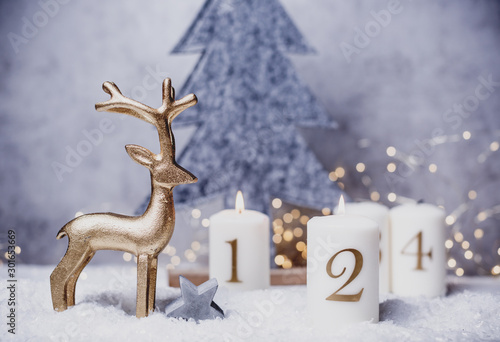 Advent candles 1, 2,3,4 in front of concrete background in the snow with colorful lights and gray trees © drubig-photo