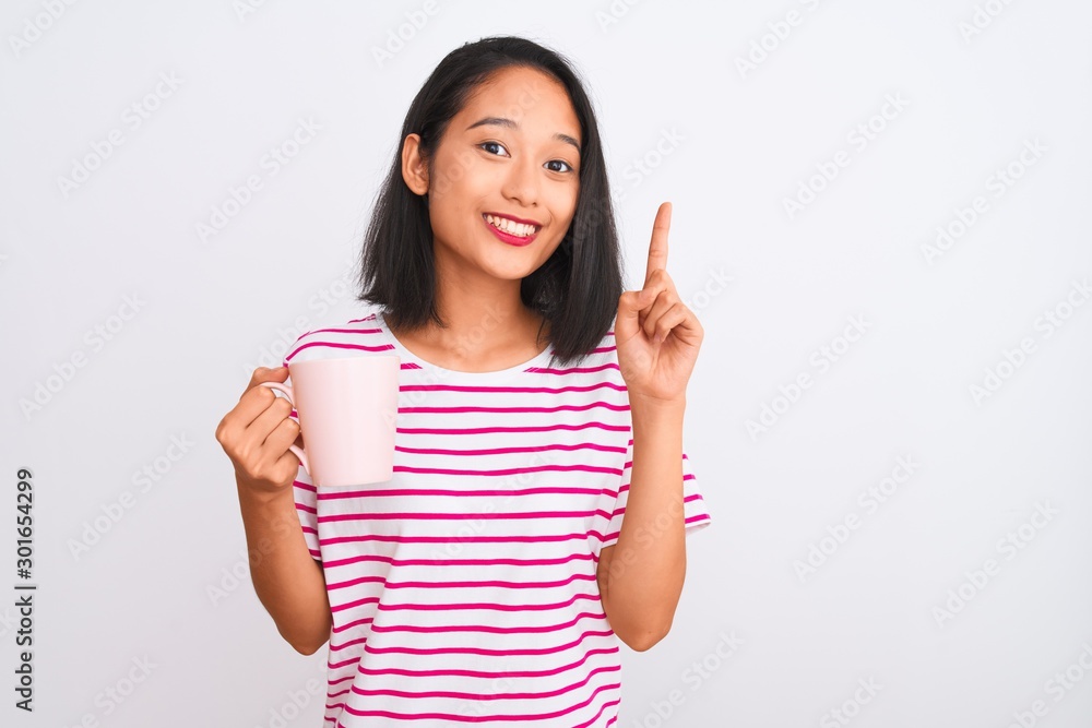 Young beautiful chinese woman drinking cup of coffee over isolated white background surprised with an idea or question pointing finger with happy face, number one Young beautiful chinese woman drinking cup of coffee over isolated white background surprised with an idea or question pointing finger with happy face, number one