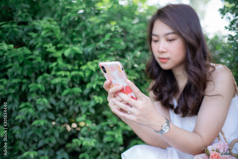 Beautiful asian women use smart phone chat message in city park Beautiful asian women use smart phone chat message in city park