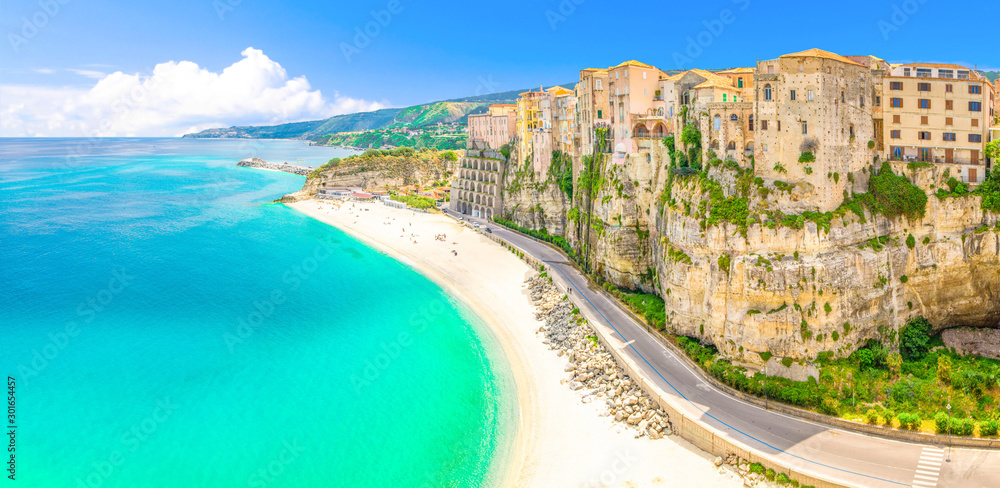 Aerial panoramic view of Tropea town and beach coastline of Tyrrhenian Sea with turquoise azure water, colorful houses buildings on top of high big rocks, road along sea, Calabria, Southern Italy