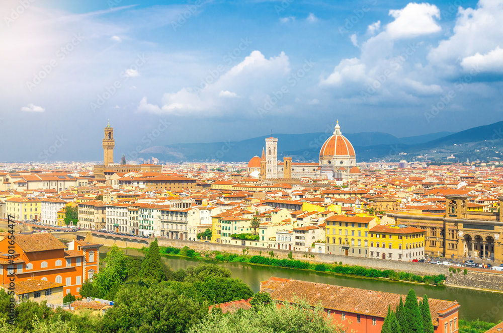 Obraz premium Top aerial panoramic view of Florence city with Duomo Cattedrale di Santa Maria del Fiore cathedral, buildings houses with orange red tiled roofs and Arno river, blue sky white clouds, Tuscany, Italy