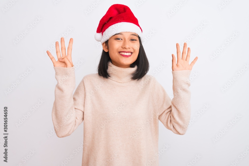 Young beautiful chinese woman wearing Christmas Santa hat over isolated white background showing and pointing up with fingers number nine while smiling confident and happy. Young beautiful chinese woman wearing Christmas Santa hat over isolated white background showing and pointing up with fingers number nine while smiling confident and happy.
