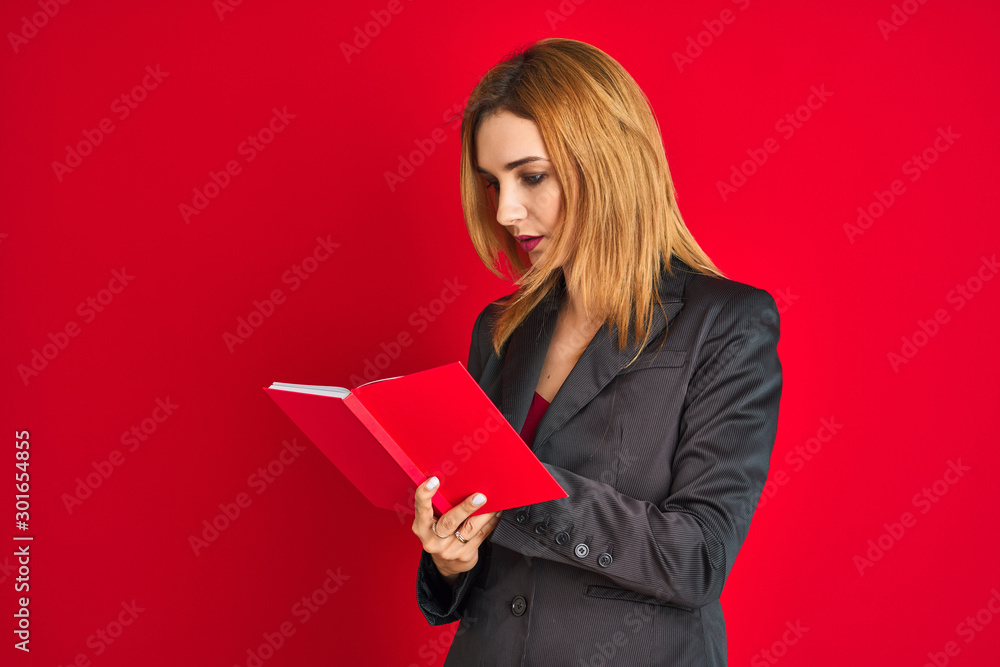 Young beautiful redhead businesswoman wearing suit reading book Young beautiful redhead businesswoman wearing suit reading book