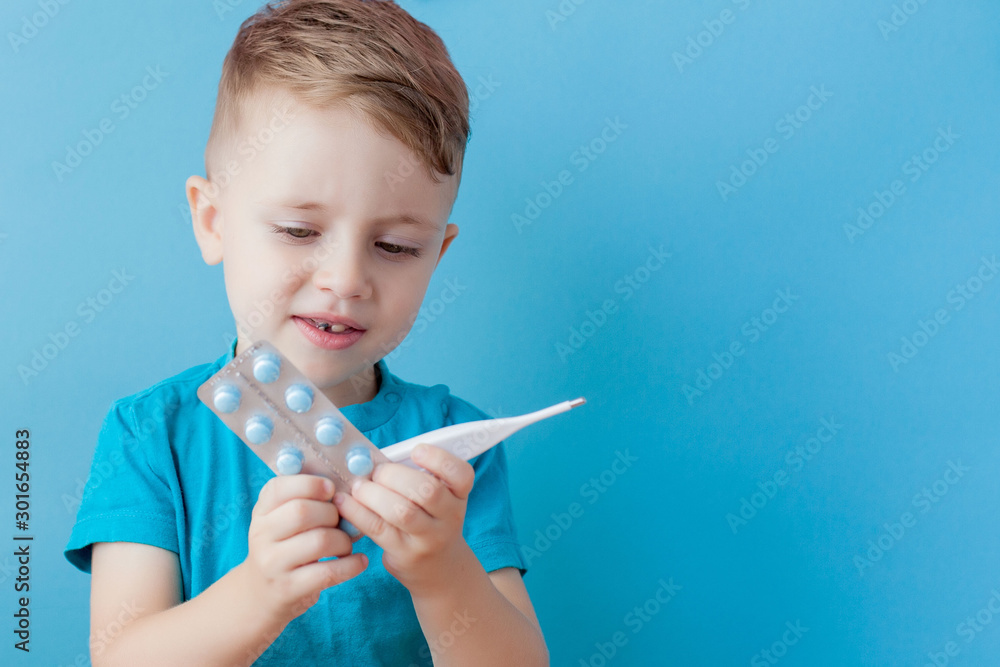 Ill young child with a thermomether, measuring the height of his fever and looking into the camera Ill young child with a thermomether, measuring the height of his fever and looking into the camera