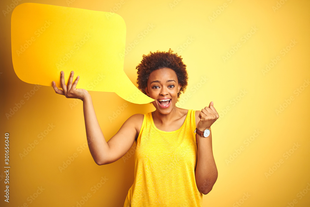 Young african american woman holding speech bubble over yellow isolated background screaming proud and celebrating victory and success very excited, cheering emotion Young african american woman holding speech bubble over yellow isolated background screaming proud and celebrating victory and success very excited, cheering emotion