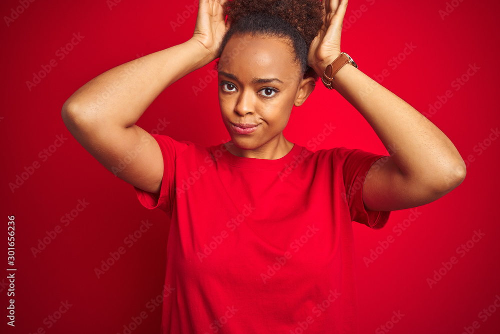 Young beautiful african american woman with afro hair over isolated red background Doing bunny ears gesture with hands palms looking cynical and skeptical. Easter rabbit concept. Young beautiful african american woman with afro hair over isolated red background Doing bunny ears gesture with hands palms looking cynical and skeptical. Easter rabbit concept.