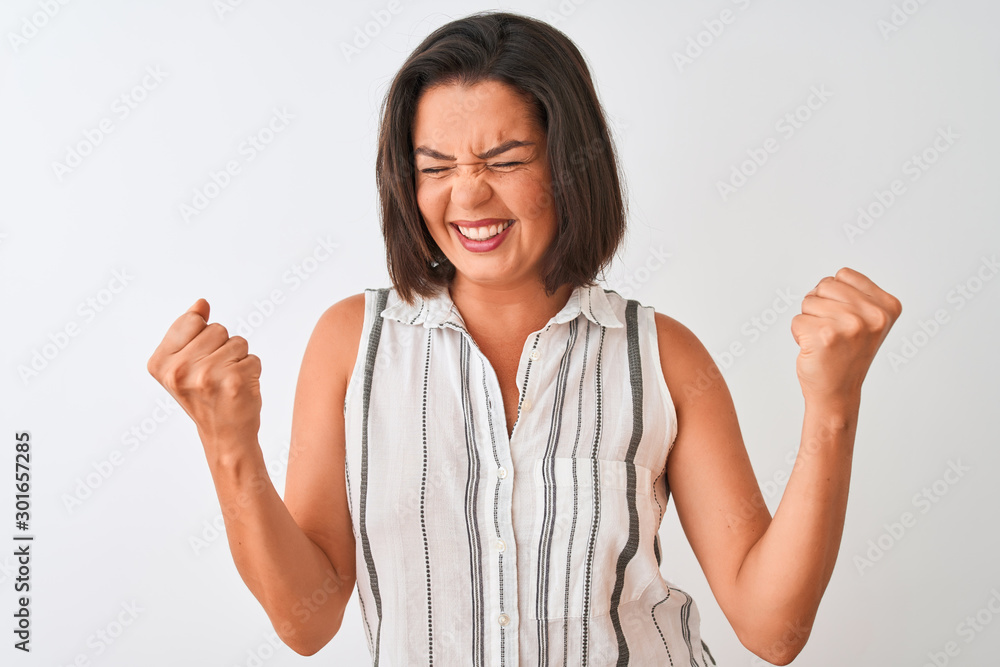 Young beautiful woman wearing casual striped shirt standing over isolated white background very happy and excited doing winner gesture with arms raised, smiling and screaming for success. Celebration Young beautiful woman wearing casual striped shirt standing over isolated white background very happy and excited doing winner gesture with arms raised, smiling and screaming for success. Celebration