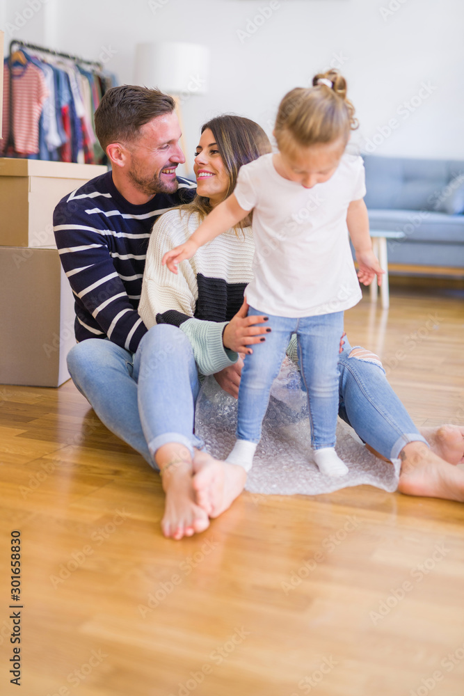 Beautiful family sitting on the floor playing with his kid at new home around cardboard boxes Beautiful family sitting on the floor playing with his kid at new home around cardboard boxes