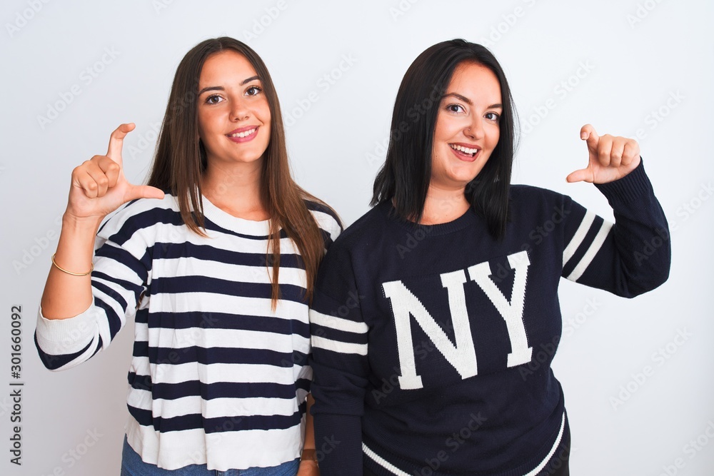 Young beautiful women wearing casual clothes standing over isolated white background smiling and confident gesturing with hand doing small size sign with fingers looking and the camera. Measure Young beautiful women wearing casual clothes standing over isolated white background smiling and confident gesturing with hand doing small size sign with fingers looking and the camera. Measure