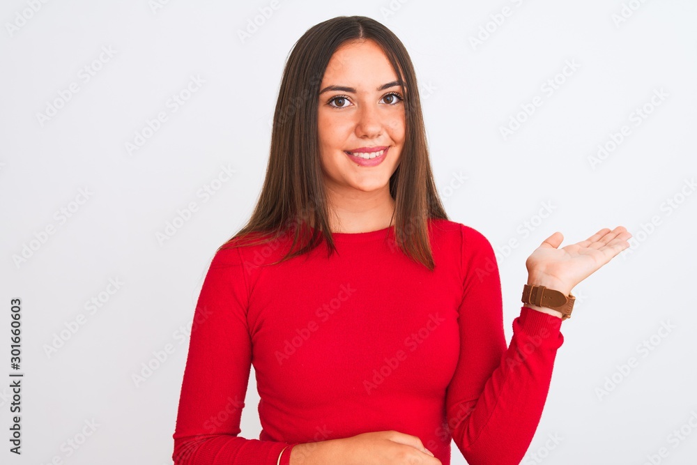 Young beautiful girl wearing red casual t-shirt standing over isolated white background smiling cheerful presenting and pointing with palm of hand looking at the camera. Young beautiful girl wearing red casual t-shirt standing over isolated white background smiling cheerful presenting and pointing with palm of hand looking at the camera.