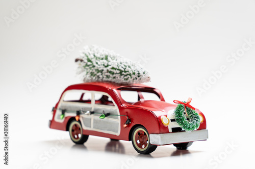 Miniature red vintage car carrying a Christmas tree on top for Xmas theme