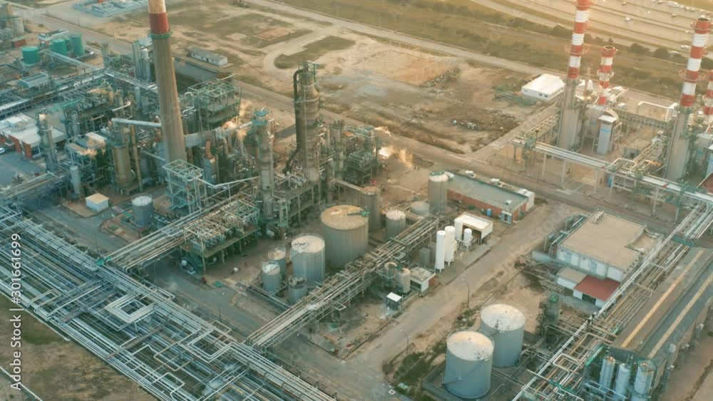 Aerial view of petrochemical oil refinery (refining complex) at sunset. Oil and gas tanks with fuming pipes on the plant (factory) Aerial view of petrochemical oil refinery (refining complex) at sunset. Oil and gas tanks with fuming pipes on the plant (factory)