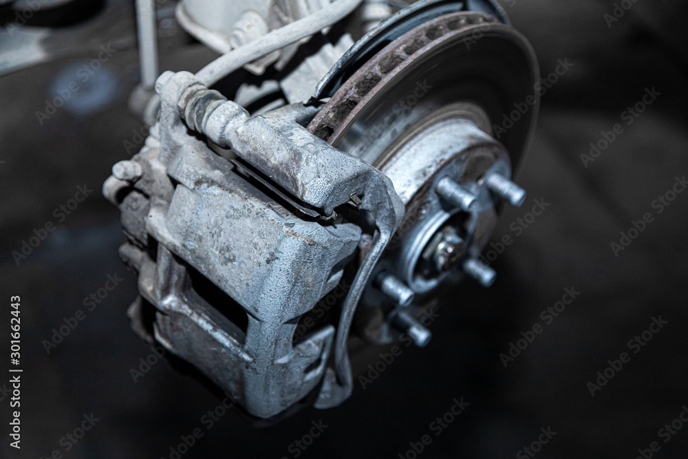 Close-up of a car hub, brake caliper, brake pads, brake disc, wheel bearing prepared for repair. Work at the tire workshop