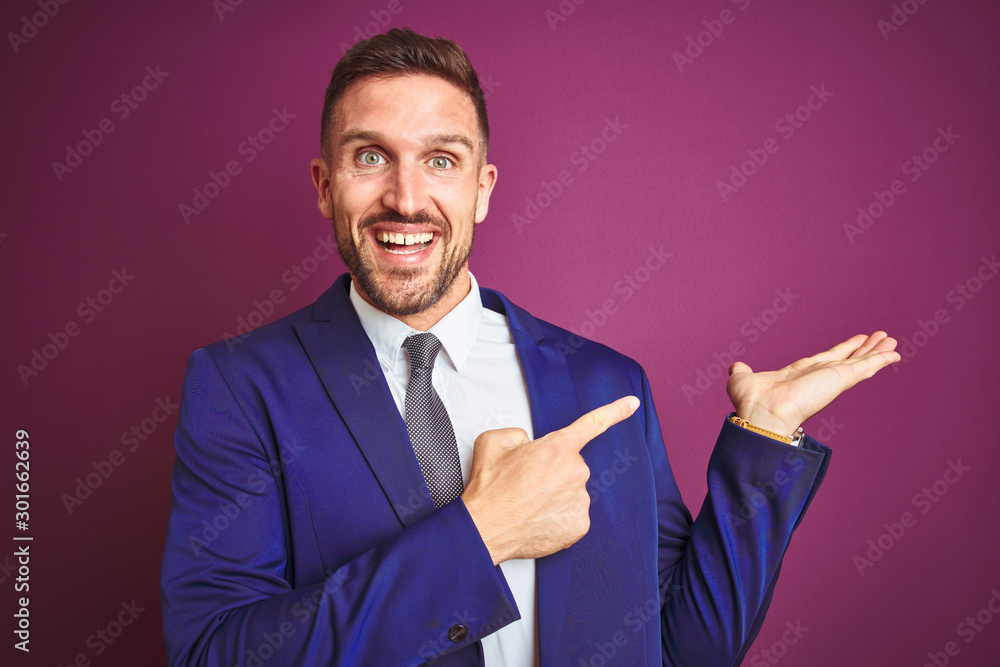 Young handsome business man over purple isolated background amazed and smiling to the camera while presenting with hand and pointing with finger. Young handsome business man over purple isolated background amazed and smiling to the camera while presenting with hand and pointing with finger.