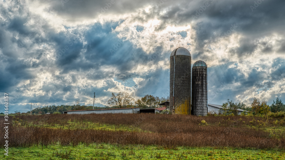 Two silos in a field on a farm on a stormy day