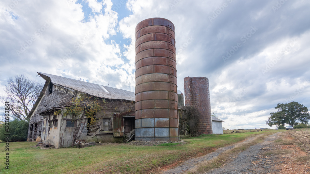 Abandoned barn with silo under stormy clouds Abandoned barn with silo under stormy clouds