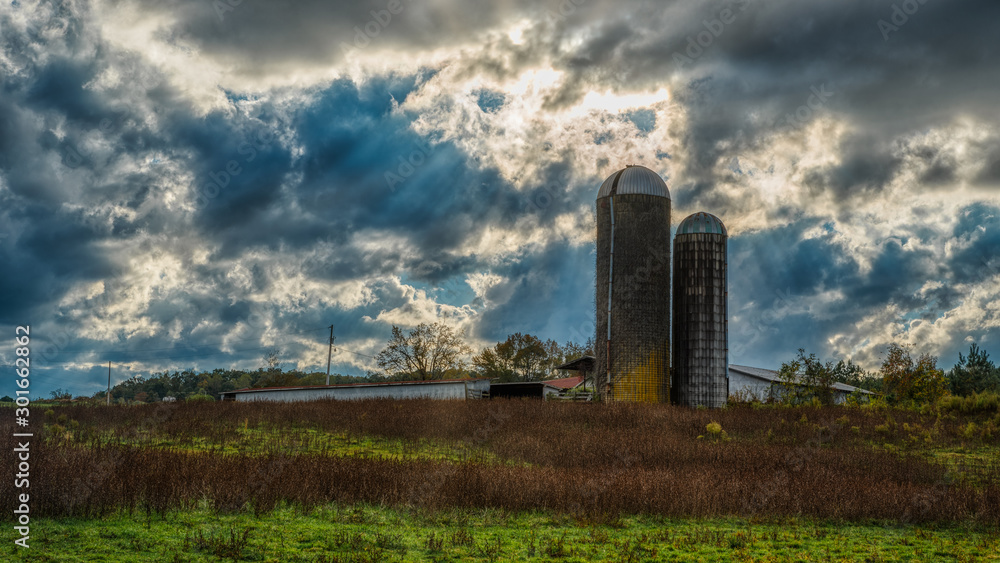 Two silos in a field on a farm on a stormy day