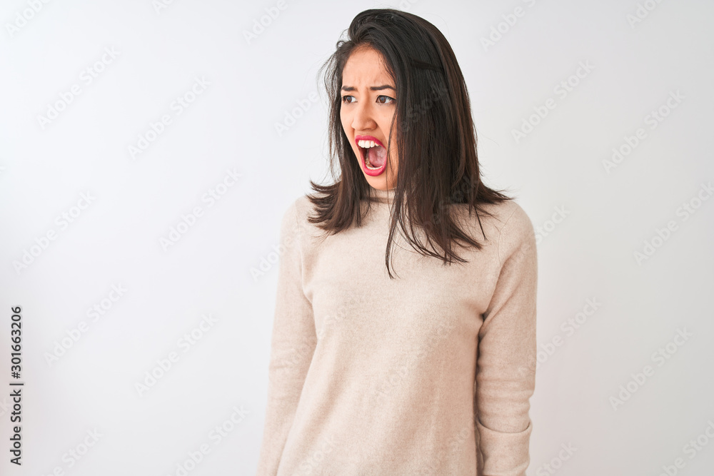 Beautiful chinese woman wearing turtleneck sweater standing over isolated white background angry and mad screaming frustrated and furious, shouting with anger. Rage and aggressive concept. Beautiful chinese woman wearing turtleneck sweater standing over isolated white background angry and mad screaming frustrated and furious, shouting with anger. Rage and aggressive concept.