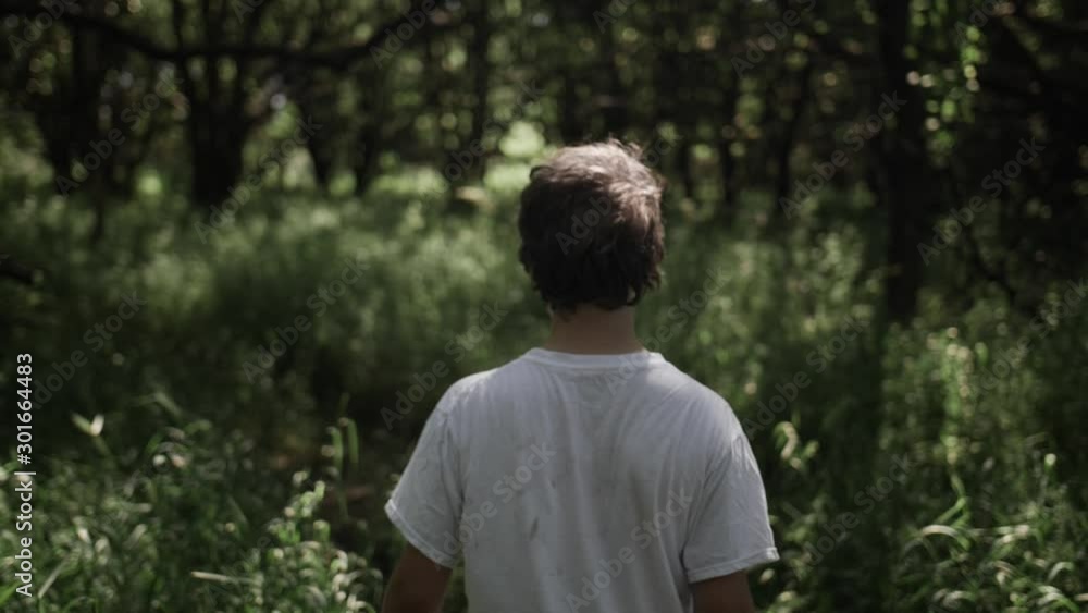 Teen boy walks through forest trees Teen boy walks through forest trees