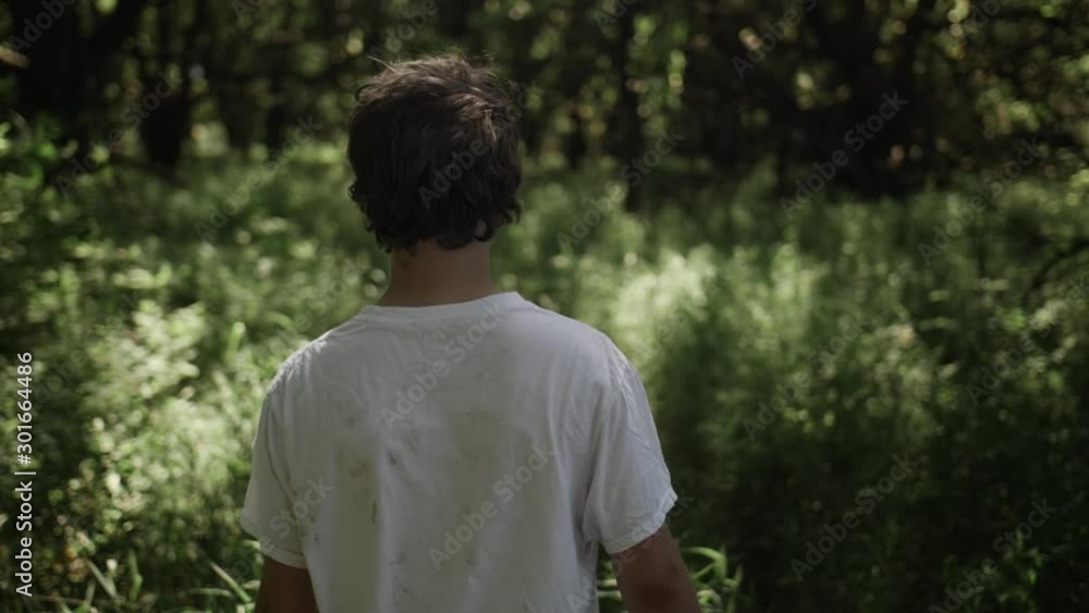 Teen boy walks through forest trees in slow motion Teen boy walks through forest trees in slow motion