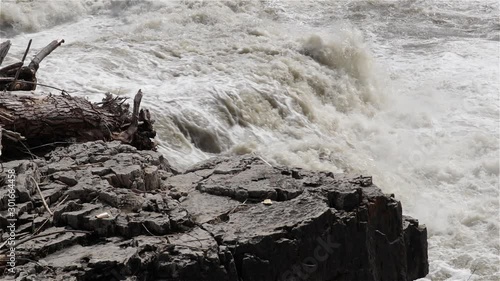 River bank of black rock and debris from raging flood waters, slowmo photo