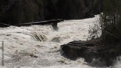 Turbulent flood waters plunge down river over jagged rocks, slowmo photo