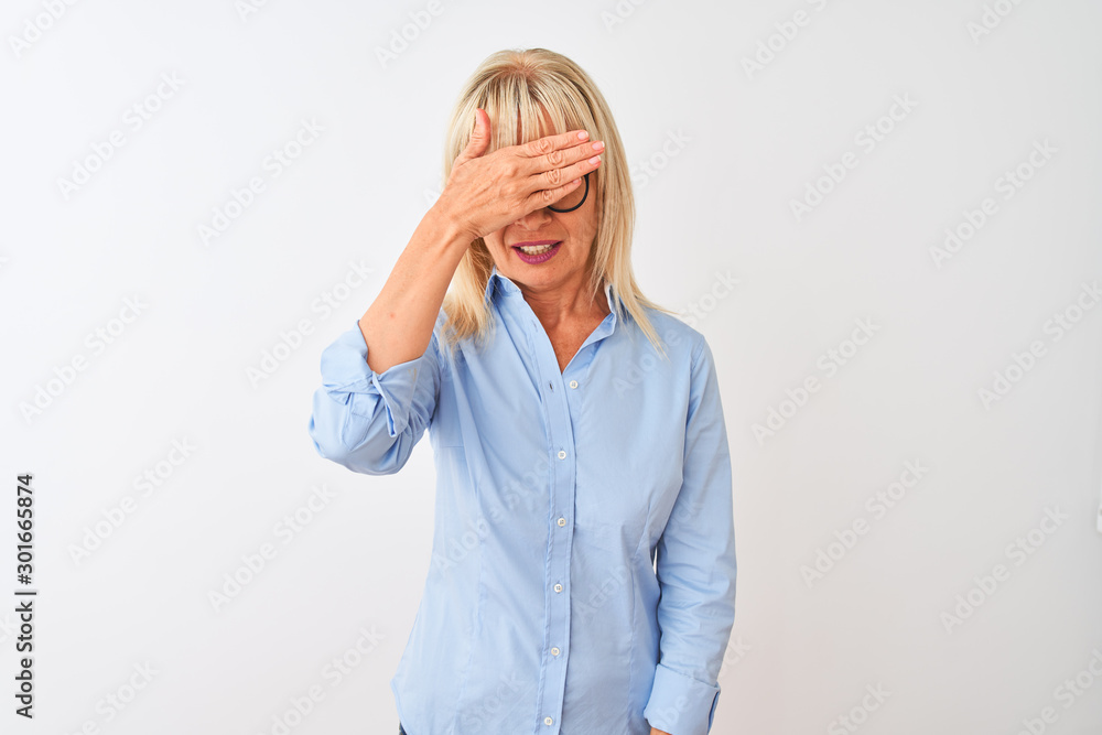 Middle age businesswoman wearing elegant shirt and glasses over isolated white background covering eyes with hand, looking serious and sad. Sightless, hiding and rejection concept Middle age businesswoman wearing elegant shirt and glasses over isolated white background covering eyes with hand, looking serious and sad. Sightless, hiding and rejection concept
