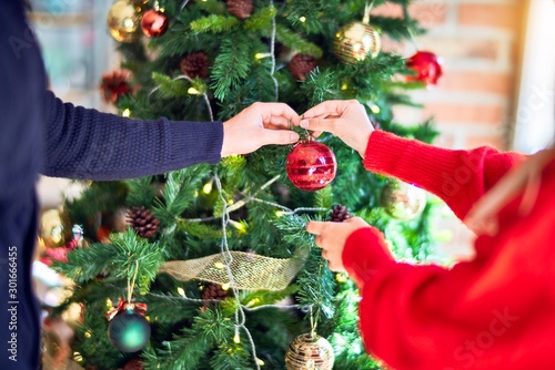 Bild auf Leinwand Young beautiful couple smiling happy and confident around christmas tree at home