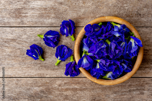 Butterfly pea or blue pea ,bluebellvine,cordofan pea(clitoria ternatea)in wooden bowl isolated on wood background. Space for text and content. Top view. photo