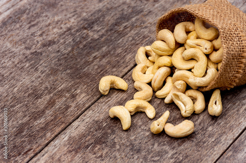 Cashew nut in sack cloth on wooden table background. 
