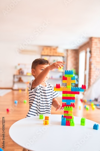 Beautiful toddler boy playing with construction blocks at kindergarten
