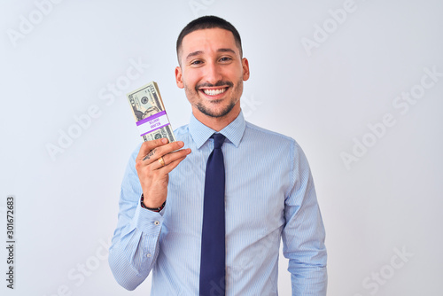 Young handsome business man holding a bunch of dollars bank notes over isolated background with a happy face standing and smiling with a confident smile showing teeth