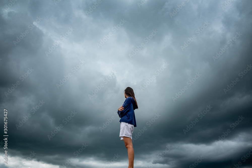 Young woman wearing loose long-sleeved sweater over stormy cloudscape, Beauty and youth Young woman wearing loose long-sleeved sweater over stormy cloudscape, Beauty and youth