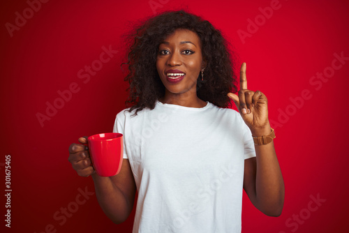Young african american woman drinking cup of coffee over isolated red background surprised with an idea or question pointing finger with happy face, number one