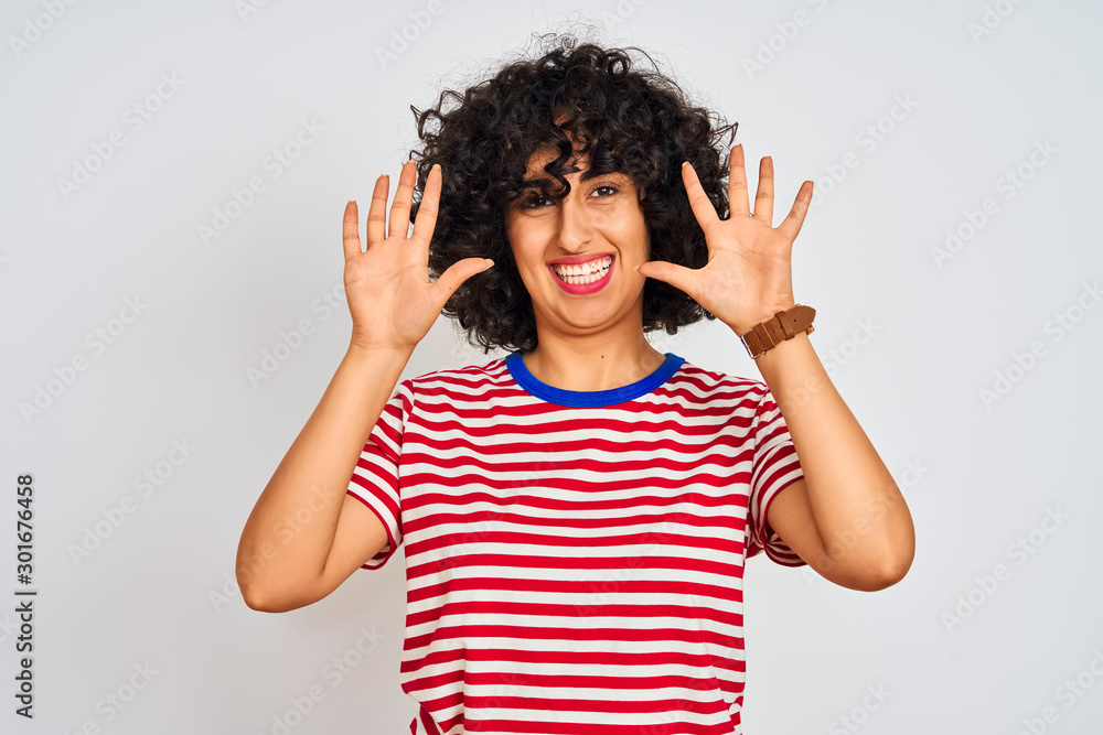 Young arab woman with curly hair wearing striped t-shirt over isolated white background showing and pointing up with fingers number ten while smiling confident and happy. Young arab woman with curly hair wearing striped t-shirt over isolated white background showing and pointing up with fingers number ten while smiling confident and happy.