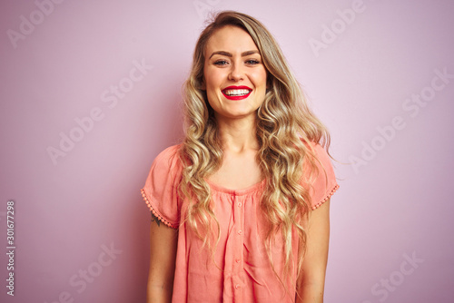 Young beautiful woman wearing t-shirt standing over pink isolated background with a happy and cool smile on face. Lucky person.
