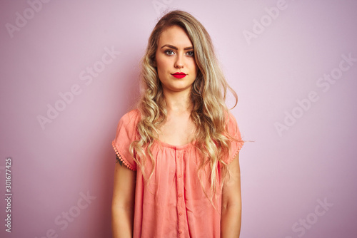 Young beautiful woman wearing t-shirt standing over pink isolated background skeptic and nervous, frowning upset because of problem. Negative person.