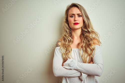 Young beautiful woman standing over white isolated background skeptic and nervous, disapproving expression on face with crossed arms. Negative person.