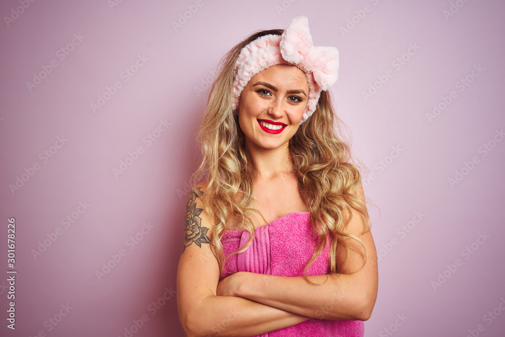 Young beautiful woman wearing towel after shower over pink isolated background happy face smiling with crossed arms looking at the camera. Positive person. Young beautiful woman wearing towel after shower over pink isolated background happy face smiling with crossed arms looking at the camera. Positive person.