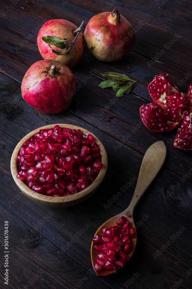 three pomegranate with bowl and wooden spoon on real wooden table three pomegranate with bowl and wooden spoon on real wooden table