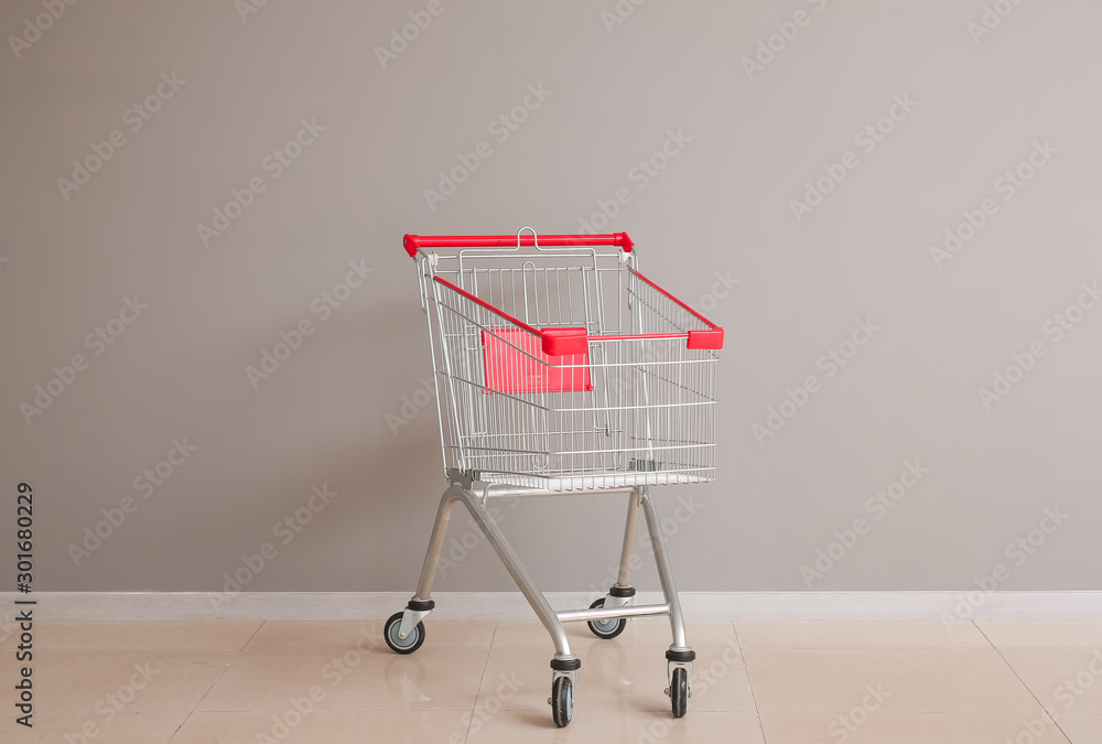 Empty shopping cart near grey wall