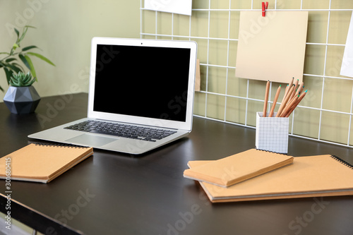 Comfortable workplace with modern laptop and moodboard near color wall © Pixel-Shot