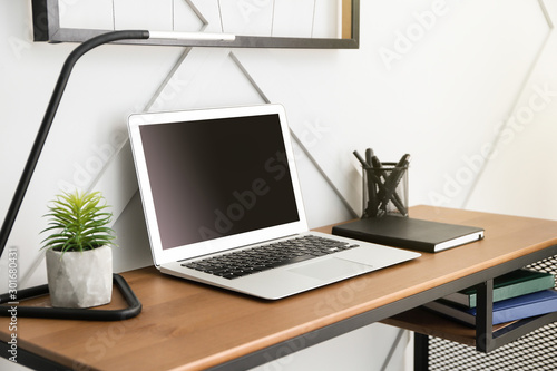 Comfortable workplace with modern laptop near light wall © Pixel-Shot