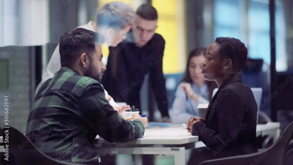 Group of intellectuals businessmen from different races discussing a new project in a glass meeting room
